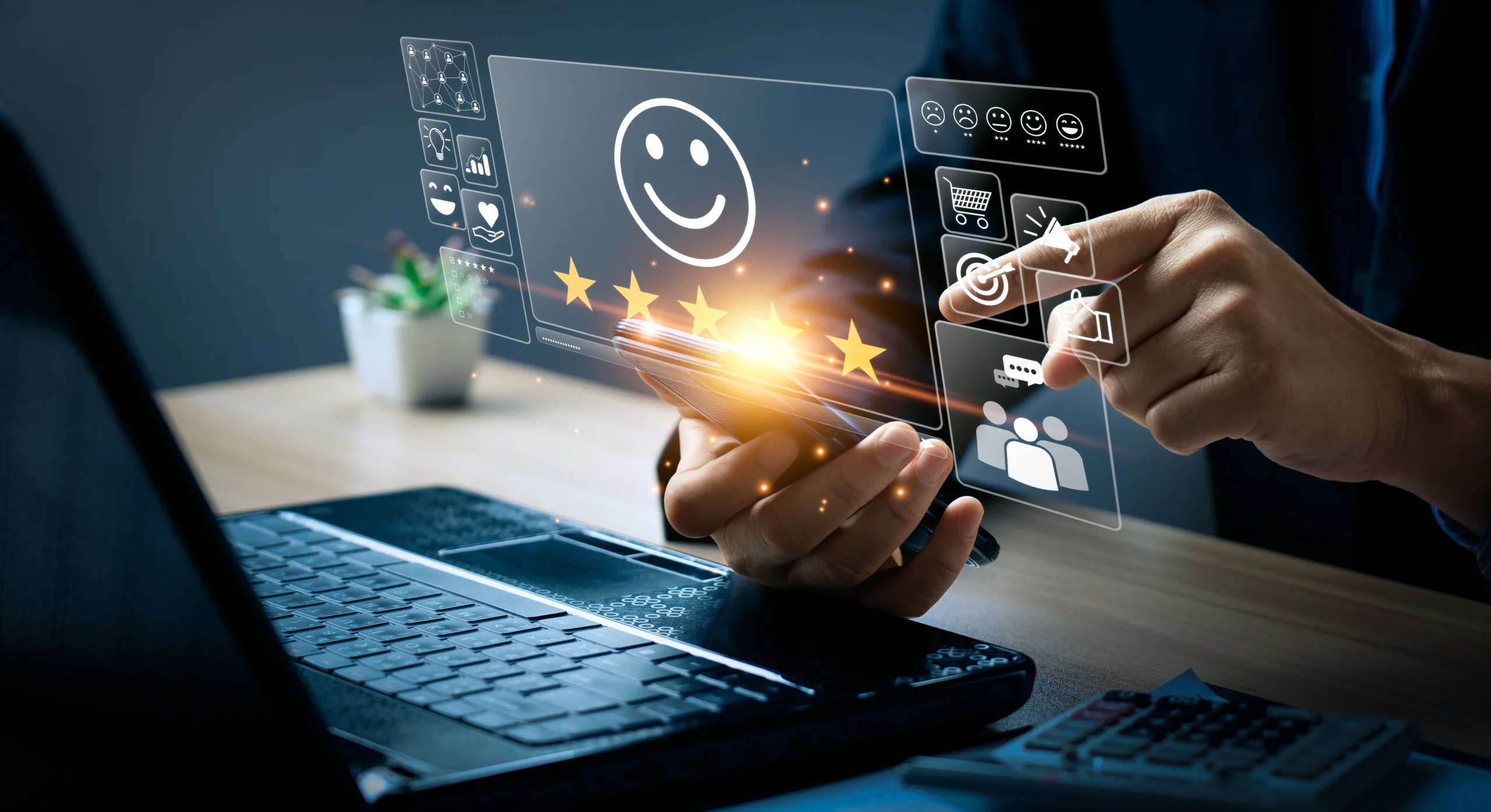 Hands holding a smartphone displaying a customer satisfaction interface with a smiling emoticon and five gold stars. A finger touches a digital overlay with icons representing positive feedback, online shopping, targeted marketing, and customer base, with a laptop and calculator nearby on a desk.